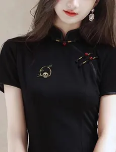 Dettaglio di una spilla a forma di panda e bambù in stile cinese su un abito Qipao nero