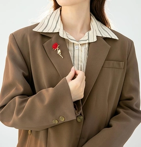 Elegant red rose brooch with gold leaves pinned on a dark suit lapel detail