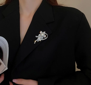 Detail of silver flower brooch with pearls and rhinestones on a black suit lapel