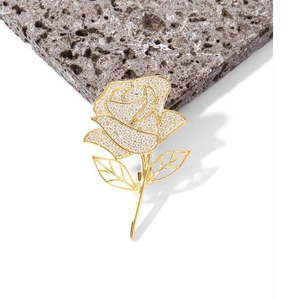 Macro detail of elegant golden rose brooch with zircon pavé setting on stone background