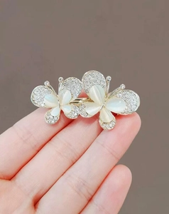 Dettaglio dell'elegante spilla a farfalla dorata con strass scintillanti e pietre opali