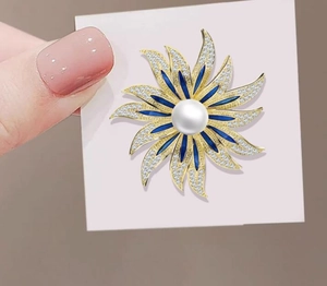 Close-up of luxury sun flower brooch with white pearl and blue enamel petals