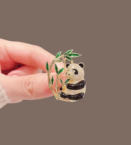 Detailed macro view of a panda brooch with emerald green enamel leaves and zircon stones