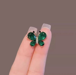 Close-up of butterfly brooch featuring four green teardrop stones and sparkling crystals