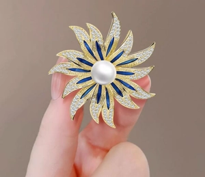 Macro view of sunflower pearl brooch with blue enamel petals and sparkling zircon inlay