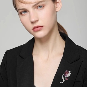Elegante silberne Blumenbrosche mit lila Kristalltropfen und Diamanten auf schwarzem Blazer