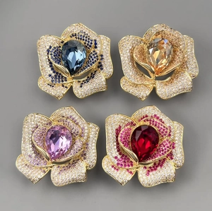 Détail de quatre broches camélia en cristal de couleurs bleu, ambre, lilas et rubis