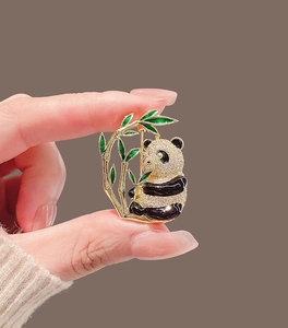 Close-up of a panda brooch with micro-pave crystals and green enamel bamboo leaves