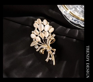 Vue macro de la broche fleur avec pierres œil-de-chat blanches et zircons sur soie