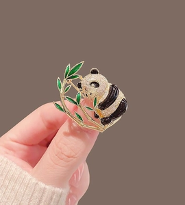 Close-up of a panda brooch featuring micro-set diamonds and green enamel bamboo leaves