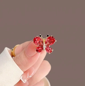 Exquisite gold butterfly brooch with faceted red gemstones and shimmering white zircons