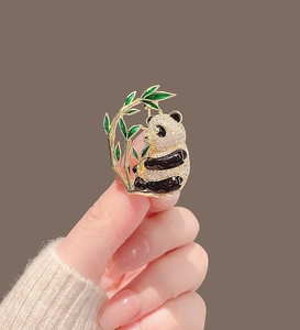 Detail of panda brooch with sparkling crystals, black enamel limbs, and green bamboo accent