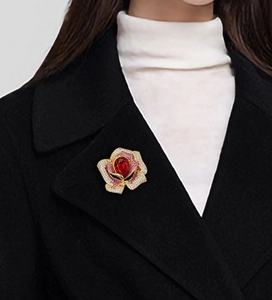 Détail de la broche camélia en cristal avec pierre rouge sur revers de manteau