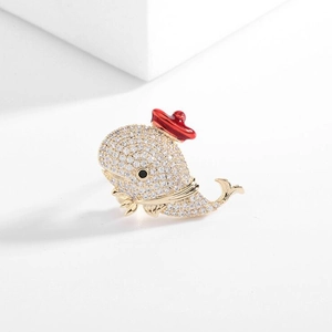 Detailed macro view of a crystal whale brooch with gold plating and red enamel hat
