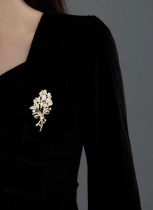 Détail d'une broche bouquet de fleurs avec opales blanches sur une veste en velours