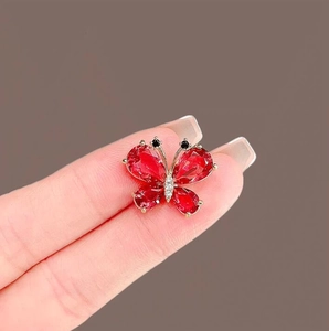 Exquisite gold-plated red crystal butterfly brooch with white diamonds on neutral background