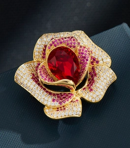 Détail macro de l'élégante broche rose avec cristal rouge et pétales étincelants