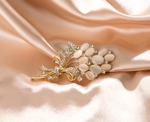 Vue détaillée d'une broche fleur dorée avec pierres œil de chat sur satin de soie