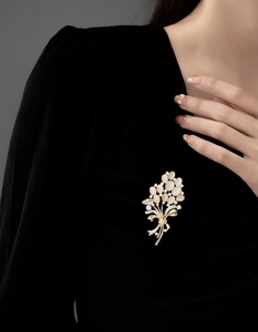 Détail d'une broche florale en œil de chat dorée avec strass sur du velours noir élégant