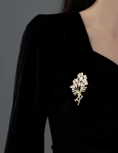 Vue détaillée d'une broche élégante en œil de chat fleurie sur une robe en velours noir