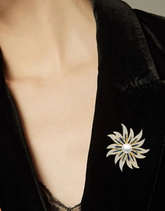 Detailed shot of a luxury pearl sunflower brooch pinned on a black velvet blazer collar