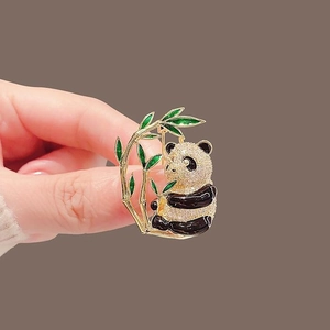 Exquisite panda eating bamboo brooch with gold base and rhinestones held by hand