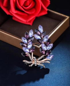 Detail of elegant leaf brooch with purple crystals and sparkling zircon accents