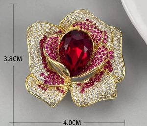 Détail d'une broche camélia en cristal avec une pierre centrale rouge en forme de poire