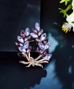 Detail of elegant purple crystal laurel wreath brooch with rose gold bow and rhinestones