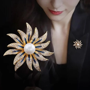 Elegant sunflower brooch with white pearl and blue enamel petals on a black suit blazer