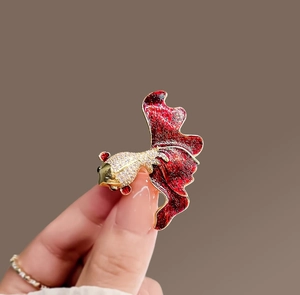 Detailed close-up of a red goldfish brooch with gold plating and sparkling cubic zirconia