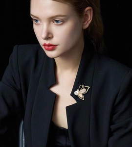 Elegant gold butterfly brooch with white pearl wings and zircon stones on black blazer