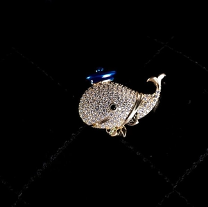 Sparkling crystal whale brooch with gold plating and blue hat detail for women