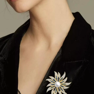 Exquisite pearl sunburst brooch with blue enamel and pavé stones on a black suit lapel