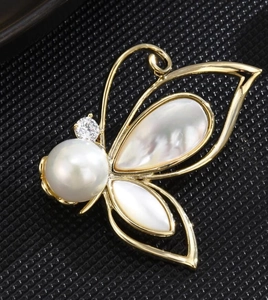 Elegant gold butterfly brooch with iridescent shell wings and a large white pearl center