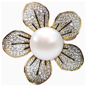 Vue détaillée d'une broche fleur dorée à cinq pétales avec perle blanche et détails noirs