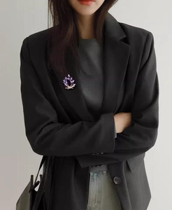 Detailed view of an elegant purple wreath brooch worn on a professional black blazer