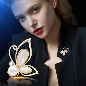 Elegant gold butterfly brooch with pearl and shell inlay on a navy blazer suit