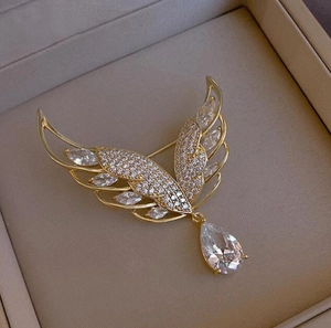Detailansicht der goldene Flügelbrosche mit Glitzersteinen und Tropfenanhänger