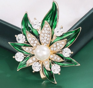 Détail macro d'une broche feuille d'érable en émail vert avec strass et perle centrale