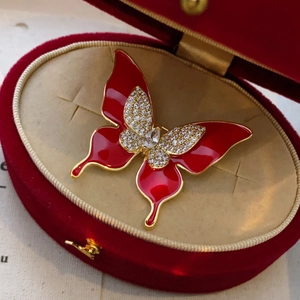 Détail de broche papillon en émail rouge avec cristaux dans un écrin en velours