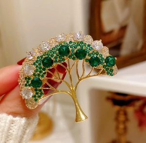 Détail d'une élégante broche sapin de Noël avec cristaux verts et finition dorée