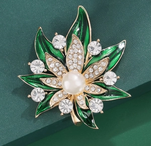 Vue détaillée de la broche feuille d'érable dorée avec émail vert, perle et strass brillants