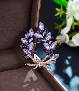 Macro shot of purple crystal floral brooch with golden finish and white rhinestones