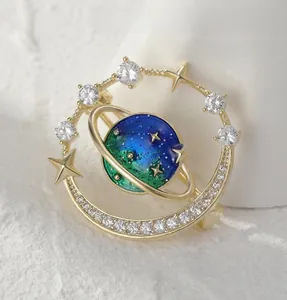 Macro view of golden planetary brooch with blue-green enamel and sparkling zircon details