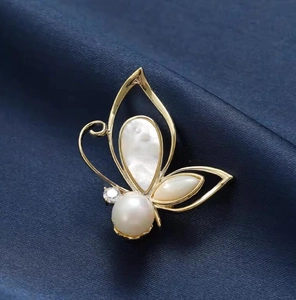 Elegant gold butterfly brooch with pearl and mother of pearl inlay on blue silk background