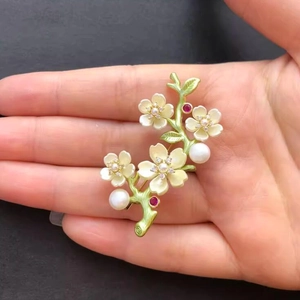 Macro shot of elegant floral brooch featuring yellow enamel petals and white pearls