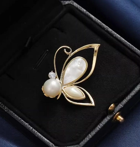 Elegant gold butterfly brooch with natural shell wings and pearls in a velvet jewelry box