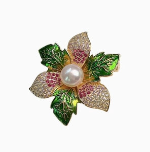 Gros plan détaillé de la broche fleur émaillée avec perle blanche et cristaux brillants