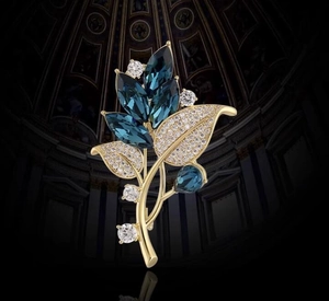 Macro detail of orchid leaf brooch with blue crystals and gold-plated finish